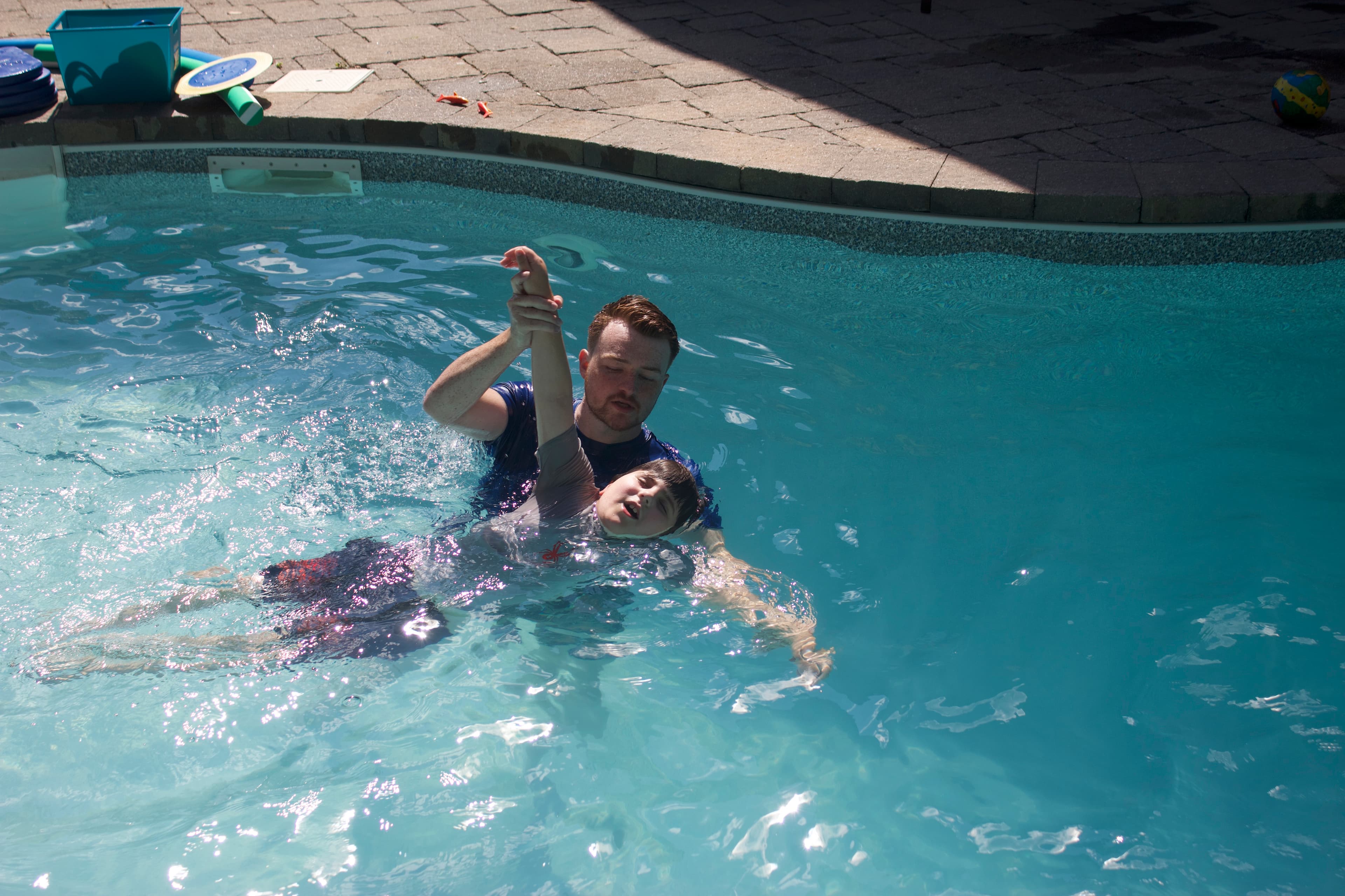 Photo of Scott helping a swimmer work on his arms for front crawl.